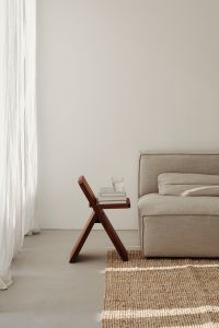 Kaboompics - Minimalist Living Room with Wooden Stool, Books, Water Glass and Large Copy Space