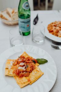 Kaboompics - Ravioli Plate with Sparkling Water and Blurred Table Setting
