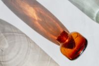Kaboompics - Amber Glass Bottle Neck Close-Up with a Sunlit Shadow