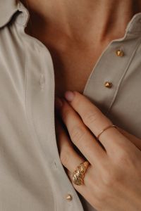 Kaboompics - Woman's Hand on Tan Silk Shirt with Gold Rings