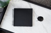 Kaboompics - Black Notebook, Wooden Bird and Green Plant Leaves on Marble Office Desk