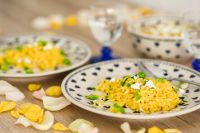 Kaboompics - Yellow rice with greens on a cute plate with blue hearts and a table decorated with flower petals