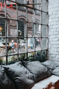 Kaboompics - Charcoal Gray Bed and Pillows beside Industrial Grid Windows and White Brick, Exhibition Interior