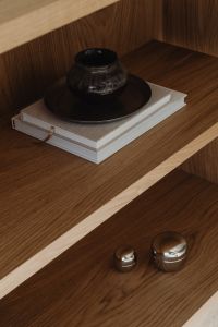 Kaboompics - Black ceramic vase on books in oak shelf