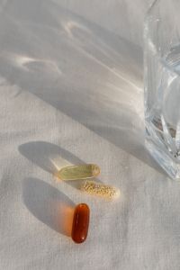 Kaboompics - Three Supplement Capsules Beside a Glass of Water