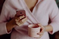 Kaboompics - A woman in a pink sweater holds a pink iPhone and a pink cup in her hands