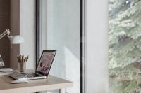 Kaboompics - Home Office Desk with Laptop and Supplies Facing a Large Window with Green Trees