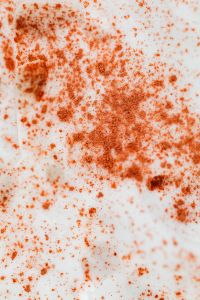 Kaboompics - Vertical Close-Up of Orange Scrub Speckles on White Skincare Cream