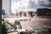 Kaboompics - Woman Reading a Book with Coffee in a Cafe Window Reflection