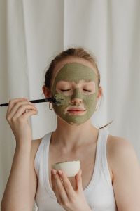 Kaboompics - Woman Applying Green Clay Face Mask with a Brush and Bowl
