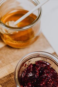 Kaboompics - Close-Up Honey and Raspberry Jam Jars on Wooden Board