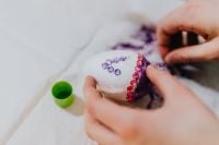 Kaboompics - Close-Up of Hands Adding Gem Stickers to a White Easter Egg