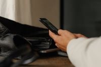 Kaboompics - Close-Up of Hand Browsing on Smartphone Beside Leather Bag