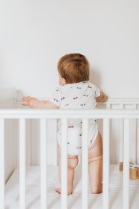 Kaboompics - Newborn Baby Standing in a White Crib in a Bright Nursery