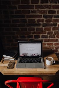 Kaboompics - Creatives desk with laptop, camera, journals and books in front of brick wall