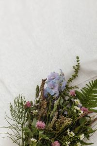 Kaboompics - Wildflower Arrangement with Ferns, Blue Flowers and Pink Clover on White Textile