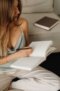 Kaboompics - Woman Writing in an Open Planner with a Pencil on Her Lap