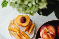 Kaboompics - Peach Slices and Whole Fruit in Tabletop Still Life with Greenery