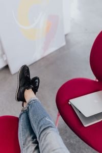 Woman using laptop computer and sitting cross legs on sofa