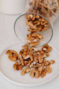 Kaboompics - Close-Up of Walnut Halves Pouring from a Glass Jar onto a White Surface