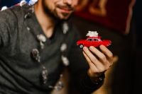 Kaboompics - Man Holding Red Toy Car beside Wrapped Christmas Presents