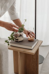 Kaboompics - Woman Styling a Potted Plant on a Wooden Side Table