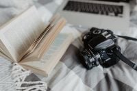 Kaboompics - A camera, MacBook, and a book waiting in bed