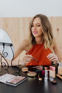 Kaboompics - Smiling Woman Pausing with Makeup Brush Beside a Vanity Mirror