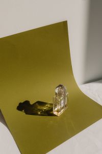 Kaboompics - Clear Perfume Bottle on Green Paper with Shadow
