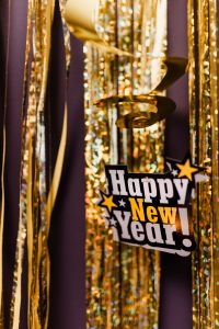 Kaboompics - Happy New Year Sign Hanging Among Gold Streamers and Champagne Details