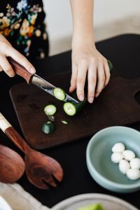 Kaboompics - Hands Slicing Fresh Cucumber with Wooden Servers and Mozzarella Bowl