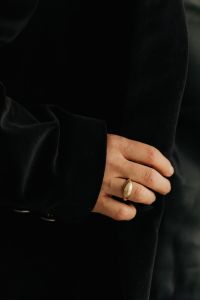 Kaboompics - Woman's Hand Gripping Black Blazer with Gold Rings