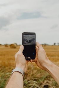 Kaboompics - Hands Using Smartphone to Photograph an Open Field