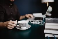 Kaboompics - Hand Holding Striped Coffee Cup beside Laptop, Earphones and Books