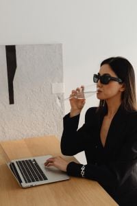 Kaboompics - Woman in Sunglasses Working on a Laptop with Wine