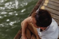 Kaboompics - Top-Down View of Man Sitting on a Lakeside Dock with Sunglasses Resting on His Head