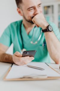 Kaboompics - Smiling Doctor Holding Smartphone in Office