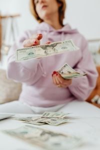 Kaboompics - Faceless Woman Holding Dollar Bills Over a Table