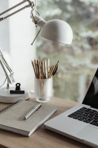 Kaboompics - Vertical Home Office Desk with Articulated Lamp, Pencils, Notebook and Laptop by a Window
