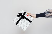Kaboompics - Hand Holding a White Reindeer-Print Gift Box with Black Ribbon, Christmas Present on White