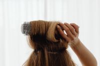 Kaboompics - Woman Combing Long Brown Hair with a Jade Comb