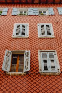 Kaboompics - Terracotta Diamond-Pattern Facade with Repeating White Shutters, Rovinj