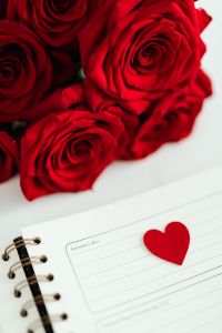 Kaboompics - Vertical Red Roses and Felt Heart on Open Planner, Valentine's Day Background