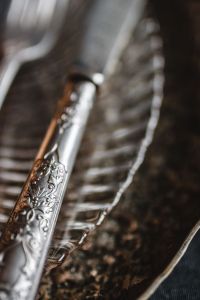 Kaboompics - Ornate Silver Dessert Knife on a Ribbed Black Plate