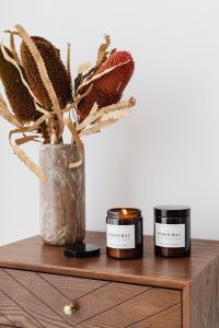 Kaboompics - Amber Candle and Black Candle Jar Beside Dried Protea for Product Photography