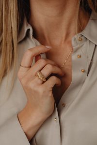 Kaboompics - Woman Touching Gold Necklace on Tan Silk Shirt