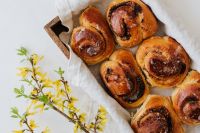 Kaboompics - Cinnamon Rolls on White Linen with Forsythia for Seasonal Bakery Content