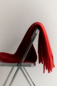 Kaboompics - Red Scarf Draped on a Transparent Chair With Copy Space