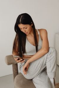 Kaboompics - Seated Woman in White Tank Top and Gray Lounge Pants, Neutral Home Portrait