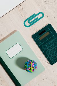 Kaboompics - Green Notebook and Teal Calculator with Colorful Rubber Band Ball for Creative Study Planning